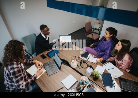 Team multirazziale che lavorano insieme in un ufficio, discutendo sulla strategia aziendale Foto Stock