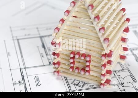 Casa realizzata da fiammiferi in piedi su piani di costruzione industria edile ristrutturazione di abitazioni agenzia immobiliare concetto di progettazione architettonica Foto Stock