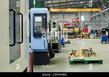 Esposizione di varie macchine e attrezzature industriali all'interno dello stabilimento di produzione con utensili disposti su pallet e scaffali sullo sfondo Foto Stock