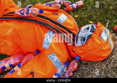 DJUPIVOGUR, ISLANDA, 21 GIUGNO: Manichino maschile giace sull'erba ricoperto di bottiglie di succo d'arancia il 21 giugno 2013 a Djupivogur, Islanda, Europa Foto Stock