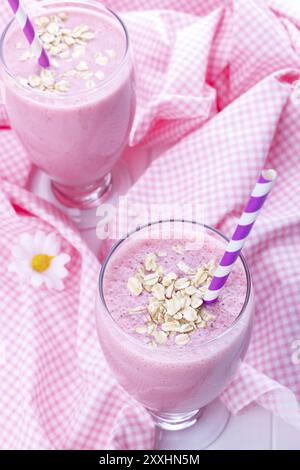 Frullato di fragole con farina di avena su bianco tavolo in legno e rosa tovaglia Foto Stock