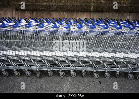 Lunghe file di carrelli vuoti che aspettano i clienti da un centro commerciale Foto Stock