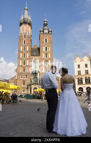 Pareja de recien casados en Rynek G?owny, plaza del mercado, basilica de Santa Maria -iglesia de la Asuncion de la Santisima Virgen Maria-, esti Foto Stock