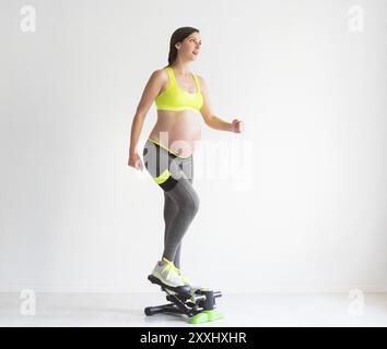 Una giovane donna incinta che fa esercizi di fitness in studio Foto Stock