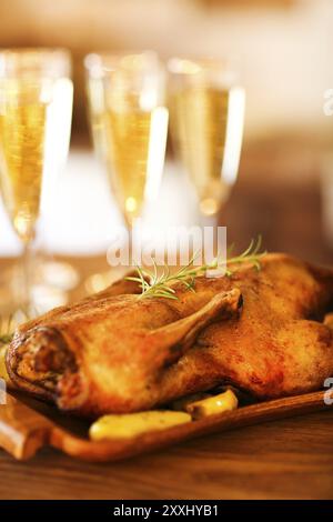 Cena di Natale con anatra arrosto e champagne sul tavolo di legno Foto Stock