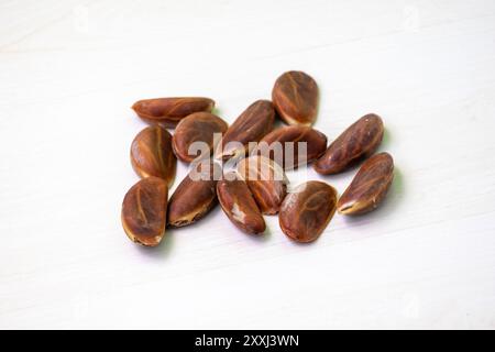 Semi di mela di velluto (Diospyros Blancoi) su una superficie di legno chiaro. Foto Stock