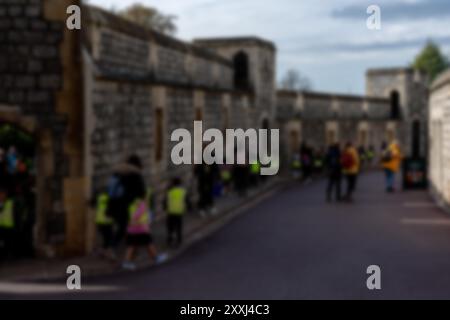 Una foto sfocata di un muro di pietra con persone che camminano davanti ad esso, con uno sfondo bokeh sfocato. Foto Stock