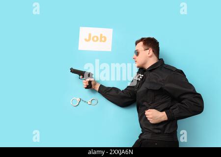 Giovane agente di polizia con pistola, manette e LAVORO di parola su sfondo blu, vista dall'alto Foto Stock