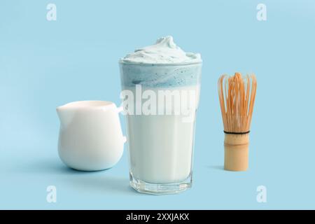 Bicchiere di dalgona blu matcha latte, caraffa e chasen su sfondo blu Foto Stock