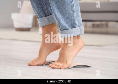 Giovane con i piedi piatti che si adattano alle solette ortopediche a casa, primo piano Foto Stock