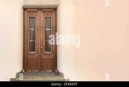 Porta chiusa vintage in legno con griglia e vetro, sfondo rosa vuoto, spazio per le copie. Cancello d'ingresso marrone neoclassico Foto Stock