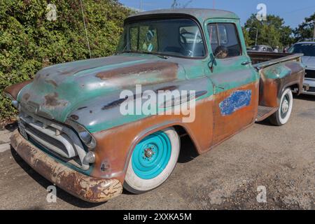 Rayleigh, Regno Unito. 25 agosto 2024. Un pick-up Chevrolet Apache 31 della fine degli anni '1950, parcheggiato all'aperto. Il veicolo è caratterizzato da una carrozzeria fortemente arrugginita con vernice verde, marrone e blu sbiadita, pneumatici whitewall e cerchi turchesi. La sua patina e le sue condizioni d'età evocano temi di nostalgia, decadenza e classica americana. Auto e camion americani si incontrano al garage Farm Fresh. L'evento consente ai proprietari di portare con sé i propri veicoli in modo che i visitatori possano osservare da vicino. Penelope Barritt/Alamy Live News Foto Stock