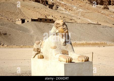 Una maestosa statua dell'antica sfinge fa da guardia al Tempio Mortuario di Hatshepsut a Deir el Bahri, in Egitto. Il paesaggio circostante è robusto Foto Stock