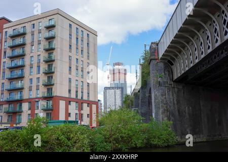 Salford, Greater Manchester, Regno Unito. 24 agosto 2024: Scena urbana moderna con edifici residenziali contemporanei a più piani adiacenti a un bri industriale Foto Stock