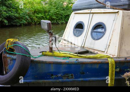 Manchester, Greater Manchester, Regno Unito. 24 agosto 2024: Una vecchia barca ancorata su un fiume sereno. L'esterno della barca mostra segni di ruggine e pai Foto Stock