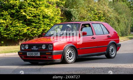 Whittlebury, Northants., Regno Unito - 25 agosto 2024: 1990 auto d'epoca Volkswagen Golf gti rossa che guida su una strada di campagna britannica. Foto Stock