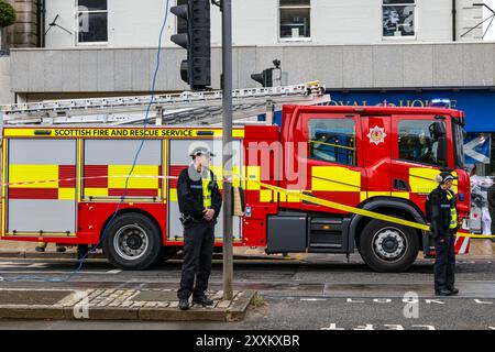 Princes Street, Edimburgo, Scozia, Regno Unito, 25 agosto 2024. I vigili del fuoco e la polizia assistono all'incidente: Due paletti al 100 Princes Street Hotel dovevano essere rimossi dai vigili del fuoco su una gru a causa di problemi di sicurezza nel vento forte con i motori antincendio che chiudevano la strada. Crediti: Sally Anderson/Alamy Live News Foto Stock