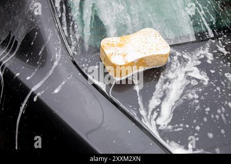 Lavaggio auto. Pulizia dell'automobile con schiuma. Veicolo coperto con detersivi chimici in schiuma shampoo durante il self-service di autolavaggio Foto Stock