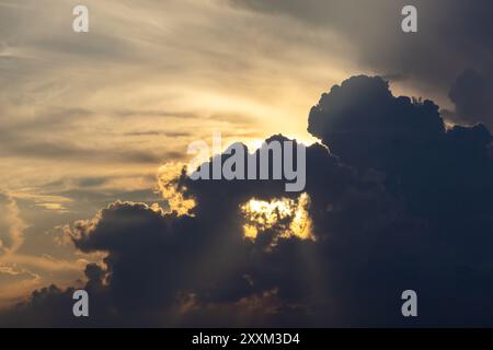 Nuvole scure che fluttuano nel cielo serale e i raggi del sole sbirciano attraverso di esse. Splendido sfondo del cielo. Foto Stock