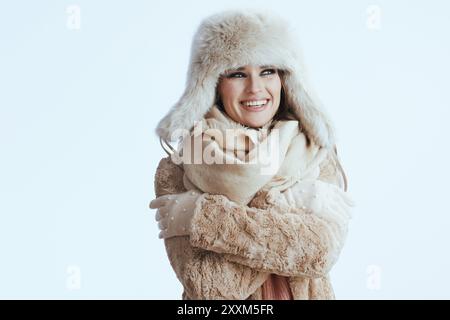 donna felice ed elegante con cappotto invernale e cappello in pelliccia isolato su sfondo bianco con guanti bianchi che si abbracciano. Foto Stock