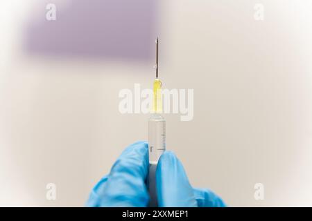 Mano del medico che tiene la siringa per il trattamento della malattia Foto Stock