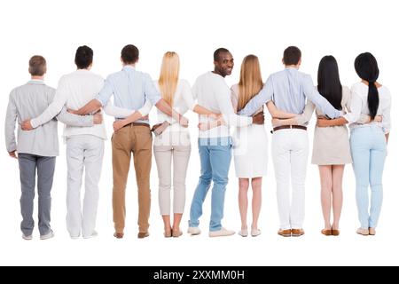 Felice di essere in squadra. Vista posteriore a tutta lunghezza di gruppi di persone diverse che si legano l'una all'altra e si trovano su sfondo bianco mentre un solo africano Foto Stock