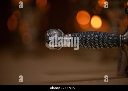 Manico con spada katana in argento medieva con motivo a corda e disegni decorati su un caldo sfondo lucente Foto Stock