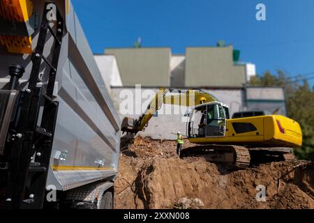 Grande escavatore è il riempimento di un dumper con terreno in corrispondenza del sito di costruzione, il progetto in corso. Foto Stock