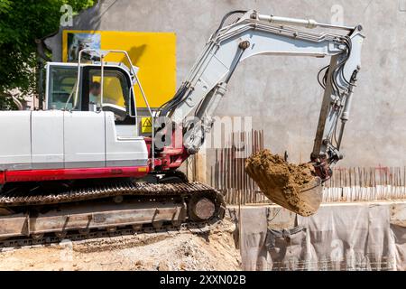 Escavatore è il riempimento di un dumper con terreno in corrispondenza del sito di costruzione, il progetto in corso. Foto Stock