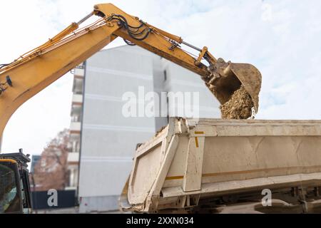 Grande escavatore è il riempimento di un dumper con terreno in corrispondenza del sito di costruzione, il progetto in corso. Foto Stock