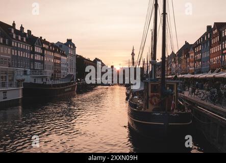 Barche lungo Nyhavn a Copenaghen al tramonto Foto Stock