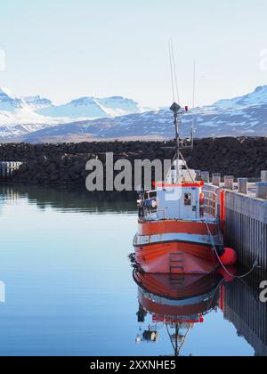 Husavik, Islanda - 12 maggio 2024: Una nave turistica piena di persone naviga in acque aperte, mostrando lo sfondo panoramico di colline innevate e ru Foto Stock