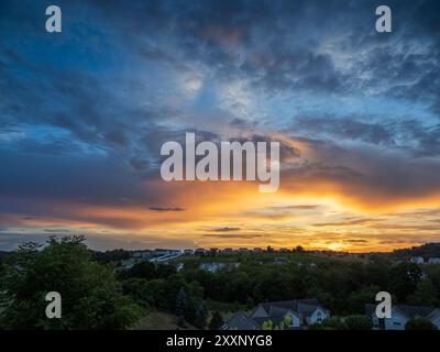 Un tramonto colorato e mozzafiato illumina il cielo estivo, proiettando vivaci sfumature sulle case suburbane della Pennsylvania, USA, trasformando la serata in un mas Foto Stock