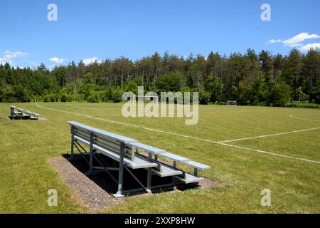 Le candeggine in alluminio si trovano vuote in un campo da calcio e sportivo in una giornata di sole d'estate. Foto Stock