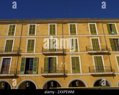 Edificio giallo e spazioso con persiane verdi e balconi, un tipico sfondo urbano, palma di Maiorca, maiorca, isole baleari, spagna Foto Stock