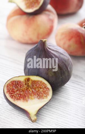 Fichi freschi e le pesche in bianco sullo sfondo di legno Foto Stock
