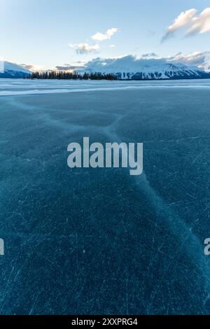 Incredibili montagne innevate in inverno con un lago ghiacciato in primo piano. Presa ad Atlin, Columbia Britannica, vicino all'Alaska, territorio dello Yukon. Foto Stock