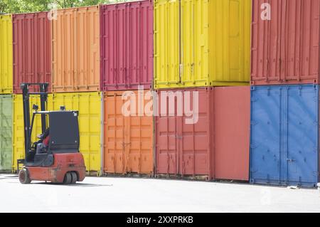 Uomo nel carrello elevatore davanti ai container Foto Stock