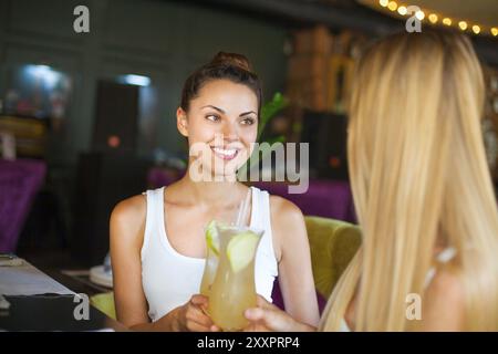 Due belle donne divertimento in un bar a bere un cocktail Foto Stock