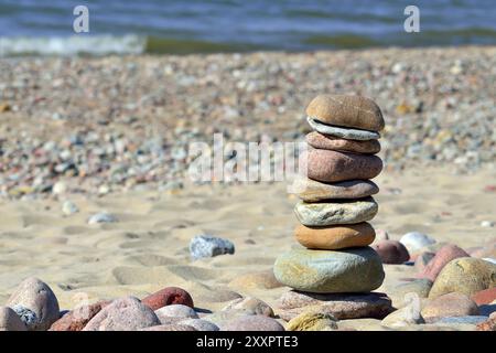 Piramide di ciottoli colorati su una spiaggia assolata Foto Stock