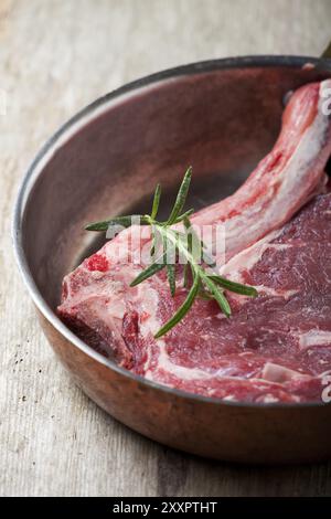 Bistecca cruda con osso a T in una padella di rame Foto Stock