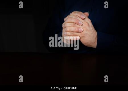 Giovane religioso che prega Dio su sfondo nero. Uomo che prega dio con le mani unite uomo caraibico che prega foto di scorta Foto Stock