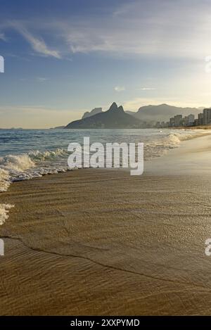 Arpoador beach in Rio de Janeiro, con edifici e il mare di pomeriggio e i due fratelli hill e Gavea sfondo stonein Foto Stock