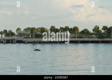 Persona isolata in kayak bianco pagaiando nel bacino di Vinoy a San Pietroburgo, Florida. Molto spazio per una copia. Niente persone. Nuvole blu e bianche in una giornata di sole Foto Stock