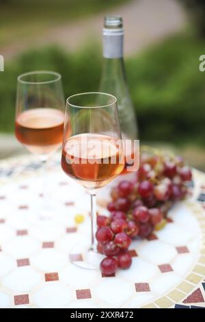 Due bicchieri e una bottiglia di vino rosato in autunno vigna sul tavolo di marmo. Epoca di vendemmia, picnic o vino tema fest Foto Stock