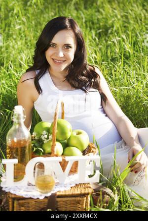 Ritratto di bella donna incinta in bianco nel Parco di primavera Foto Stock