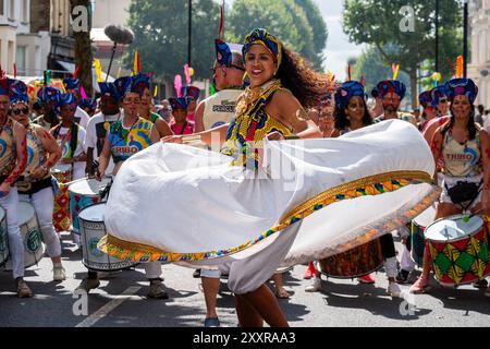 Londra, Regno Unito. 25 agosto 2024. Un ballerino si esibisce di fronte ai batteristi durante il carnevale di Londra. Il Carnevale di Notting Hill è uno dei festival di strada più grandi del mondo. Si tratta di un carnevale caraibico annuale che si svolge a Londra dal 1966 sulle strade di Notting Hill durante il fine settimana festivo di agosto. Credito: SOPA Images Limited/Alamy Live News Foto Stock