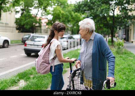 Nonna che spiega alla nipote come guidare uno scooter in sicurezza prima di partire per la scuola. Foto Stock