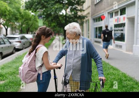 Nonna che spiega alla nipote come guidare uno scooter in sicurezza prima di partire per la scuola. Foto Stock