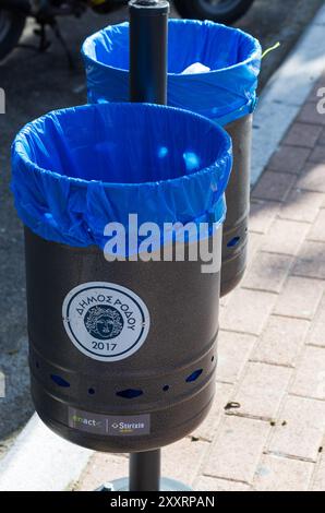 Rodi, Grecia - 21 settembre 2017: Doppio rack con cestini e sacchetti blu inseriti con il logo del comune di Rodi Foto Stock